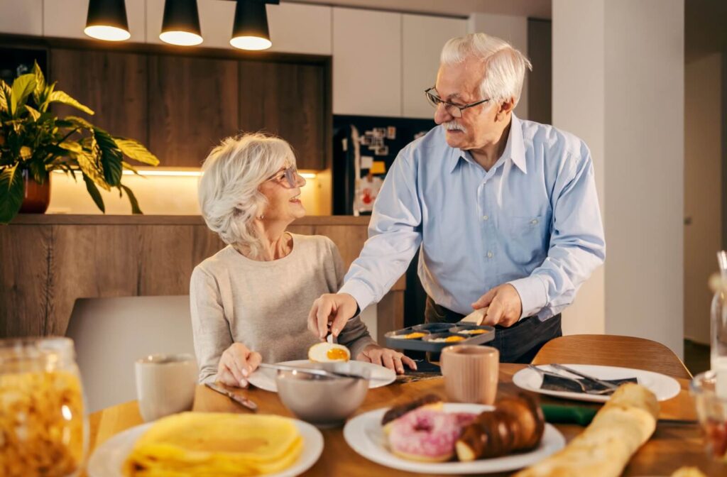 A senior places a sunny-side-up egg on their partner's breakfast plate, starting their mornings with protein-rich meals